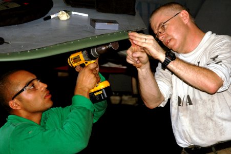 US Navy 070815-N-8119R-028 Aviation Structural Mechanic 1st Class Richard Aillet holds part of the horizontal stabilizer as Aviation Structural Mechanic 3rd Class Israel Martinez sands down rough spots on an F-A-18C Hornet photo
