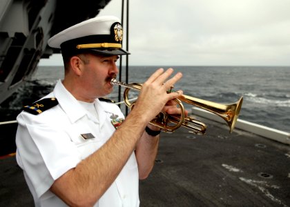 US Navy 070819-N-7981E-122 Chief Warrant Officer 3 Rob Holland plays taps at the completion of a burial at sea ceremony aboard Nimitz-class aircraft carrier USS Abraham Lincoln (CVN 72) photo