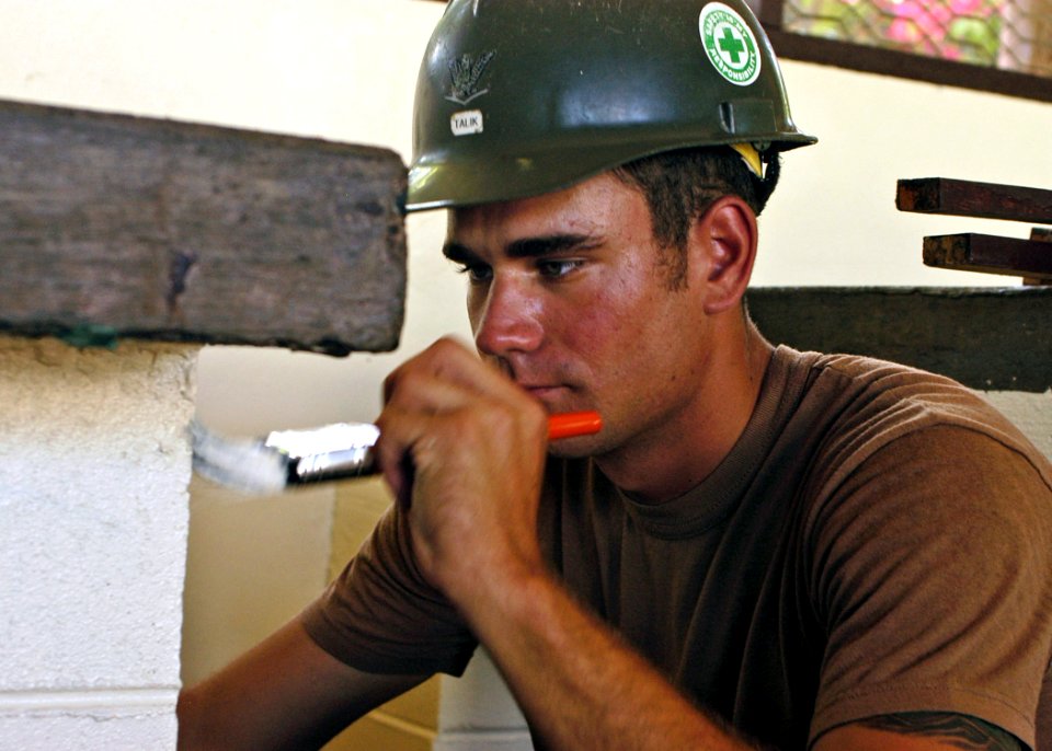 US Navy 070814-N-6999H-037 Construction Electrician 3rd Class Jared Talik attached to Naval Mobile Construction Battalion (NMCB) 7 touches up trim during a engineering civil assistance program