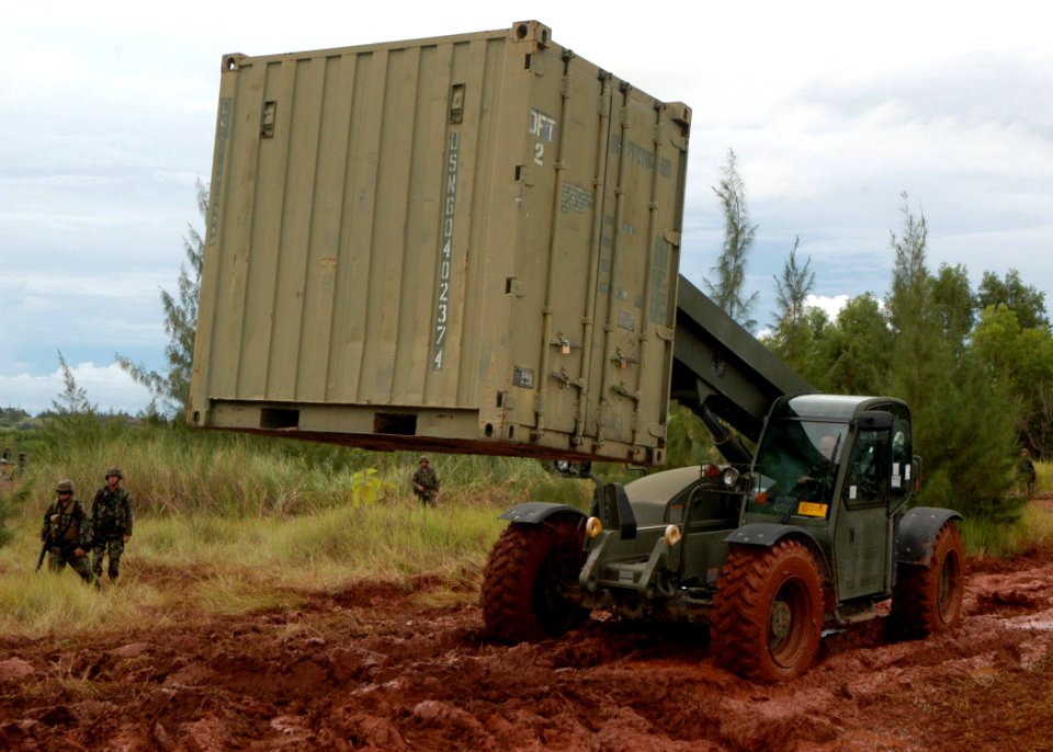 US Navy 070820-F-8678B-050 Construction Mechanic 1st Class Kenneth E. Terlaan drives a extendable boom forklift through the mud to position a CONEX box containing the field armory during setup for a field exercise
