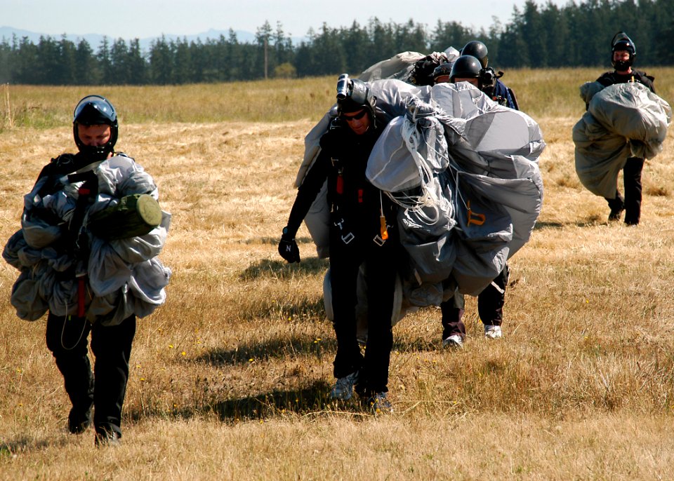 US Navy 070815-N-9860Y-048 Members of Explosive Ordnance Disposal Mobile Unit (EODMU) 11 walk with their parachutes after landing during a jump to honor fallen comrades in Outlying Field