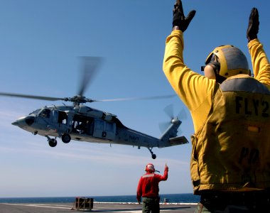 US Navy 070818-N-8923M-111 A plane director signals for an MH-60 Seahawk, from Helicopter Combat Support Squadron (HSC) 2, to lift up after unloading ordnance onto the flight deck of Nimitz-class aircraft carrier USS Harry S. T
