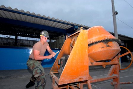 US Navy 070819-N-8704K-011 Builder 2nd Class Charlie Page, a Seabee with Construction Battalion Maintenance Unit (CBMU) 20, starts a concrete mixer to lay wheelchair ramps at the Luis Teodoro Cantos School photo