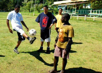 US Navy 070819-N-1752H-045 Aviation Boatswain's Mate (Handling) 3rd Class Delron Cowan attached to USS Peleliu (LHA 5) demonstrates his soccer skills to local children prior to a community relations (COMREL) soccer game