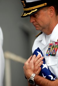 US Navy 070819-N-7981E-325 Capt. Patrick D. Hall, commanding officer of Nimitz-class aircraft carrier USS Abraham Lincoln (CVN 72), carries a flag to present to the wife of Lt. Cmdr. Glen Hansen during a burial at sea aboard Li photo