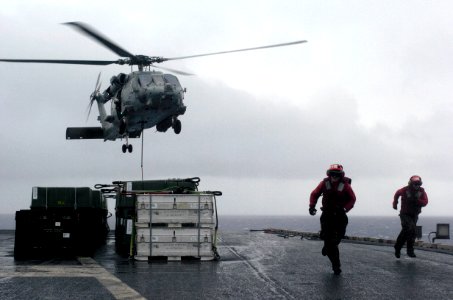 US Navy 070818-N-3038W-996 Two Sailors clear the loading area after attaching a cargo pendant to an HH-60H Seahawk