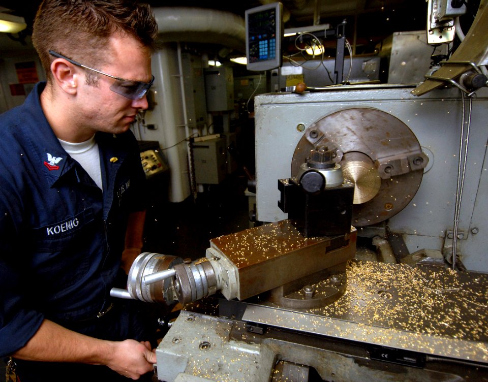 US Navy 070822-N-8923M-142 Machinery Repairman 2nd Class Patrick Koenig machines metal on a lathe in the machine shop of Nimitz-class aircraft carrier USS Harry S. Truman (CVN 75)