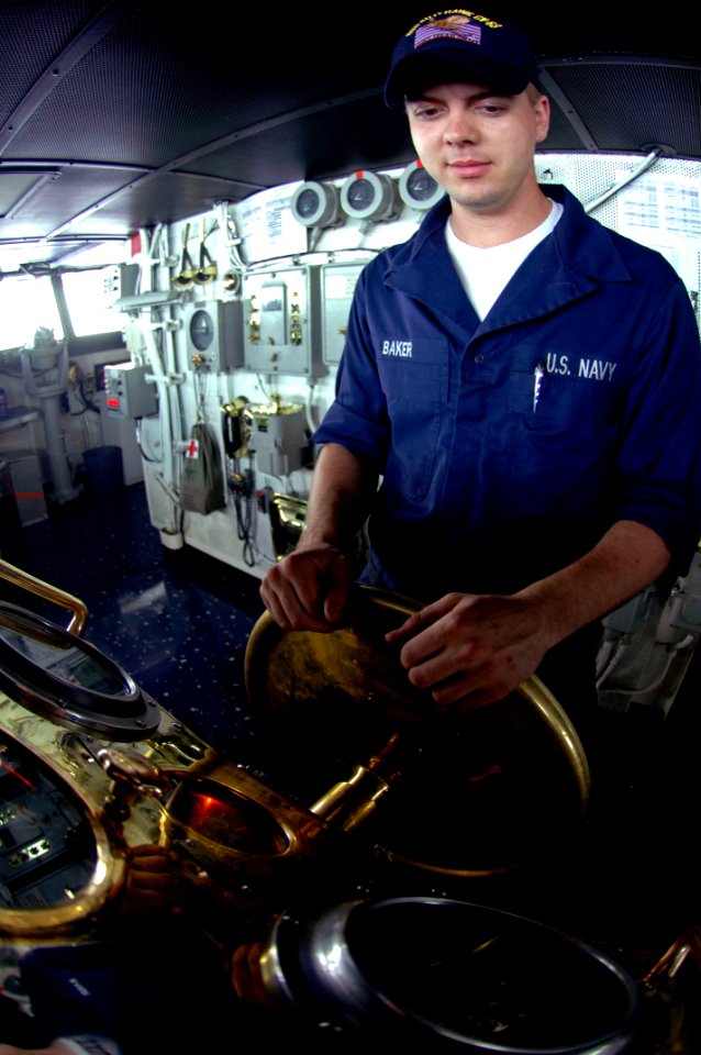 US Navy 070821-N-7883G-004 Boatswain's Mate Seaman Chris Baker stands helmsman watch on the bridge aboard USS Kitty Hawk (CV 63). As helmsman, Baker is responsible for steering the ship
