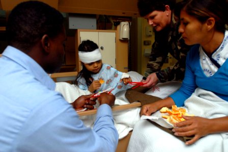 US Navy 070820-N-4238B-002 Tech. Sgt. Carol Connatser and Hospital Corpsman 1st Class Samuel McFall, both attached to Military Sealift Command hospital ship USNS Comfort (T-AH 20), give a handmade bracelet to a recovering child photo