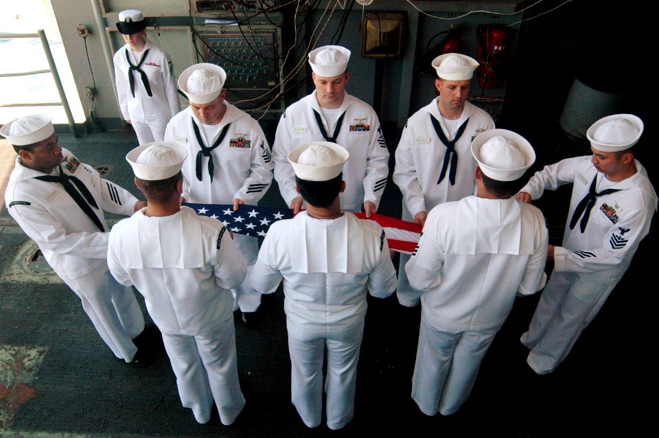 US Navy 070822-N-3136P-027 First class petty officers selected for chief petty officer fold a flag during a ceremony aboard USS Kitty Hawk (CV 63) for the Battle of Leyte Gulf