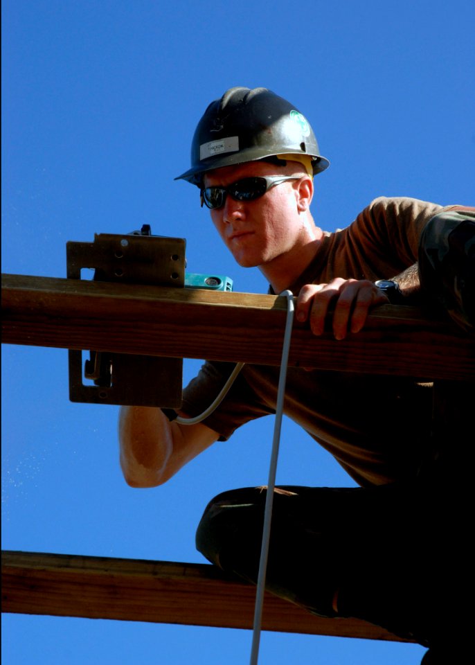 US Navy 070822-N-4267W-004 Steelworker 3rd Class Ben Hickok, assigned to Naval Mobile Construction Battalion (NMCB) 7, uses a circular saw to trim the frame of a roof for a new medical clinic