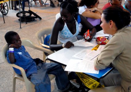 US Navy 070823-N-7092S-026 A child and his mother are consulted by nurse anesthetist Cmdr. Carole Daniel at the Military Sealift Command hospital ship USNS Comfort (T-AH 20) medical site at the Buenaventura Coliseum