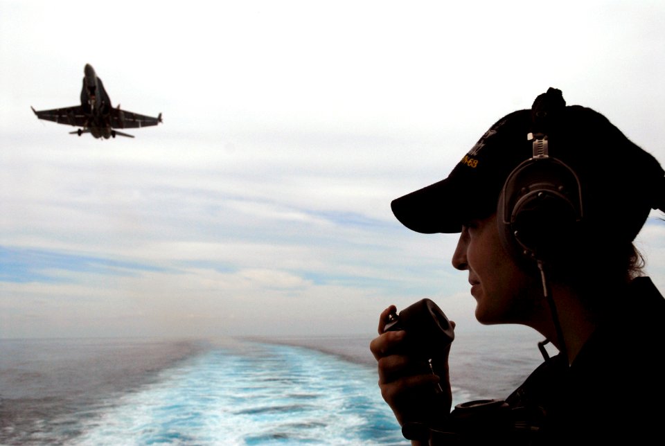 US Navy 070825-N-0890S-072 Seaman Monica Kreinheder talks on a sound-powered phone while standing aft lookout as an F-A-18C Hornet prepares to land on the flight deck of the nuclear-powered aircraft carrier USS Nimitz (CVN 68)