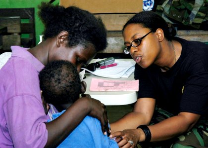 US Navy 070823-N-9195K-069 Lt. Tracy Branch, of the United States Public Health Services, comforts a local child before examining him during a medical screening at Voza Medical Clinic in support of Pacific Partnership photo