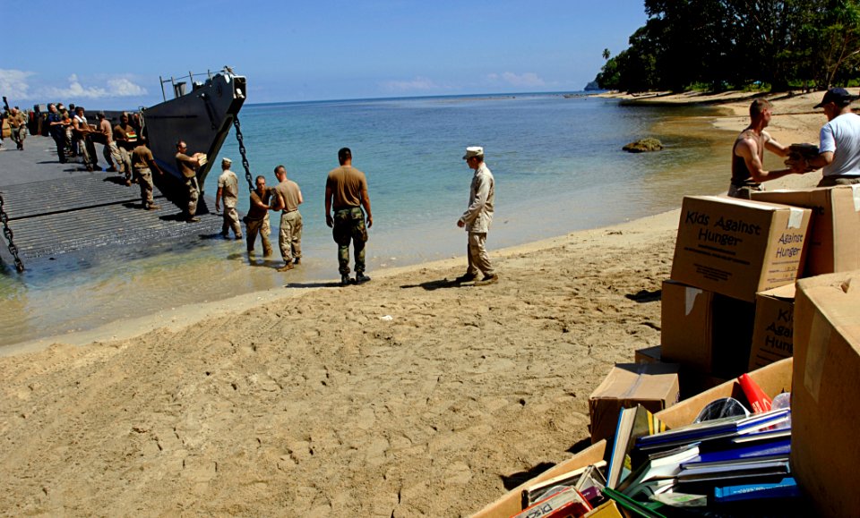 US Navy 070823-N-4954I-087 Seabees attached to Amphibious Construction Battalion (ACB) 1, unload Project Handclasp supplies from Landing Craft Unit (LCU) 1665