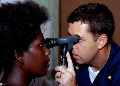 US Navy 070823-N-9195K-077 Lt. Cmdr. Matt Behil uses a ophthalmoscope to check a local woman's eyes during a medical civic action program at Voza Medical Clinic in support of Pacific Partnership photo