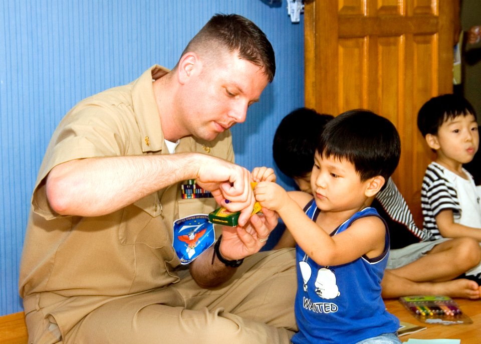 US Navy 070825-N-0483B-002 Senior Chief Cryptologic Technician (Technical) Robert Stewart, 7th Fleet staff member embarked aboard amphibious command ship USS Blue Ridge (LCC 19), colors with a child of the Aehyang Children's We