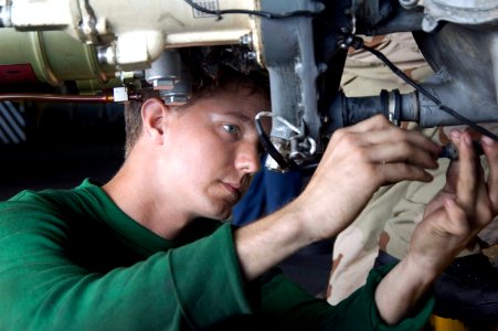 US Navy 070824-N-5387K-015 viation Electrician's Mate 3rd Class Richard Stevenson tightens screws on the main gear box wire harness of an SH-60F Seahawk