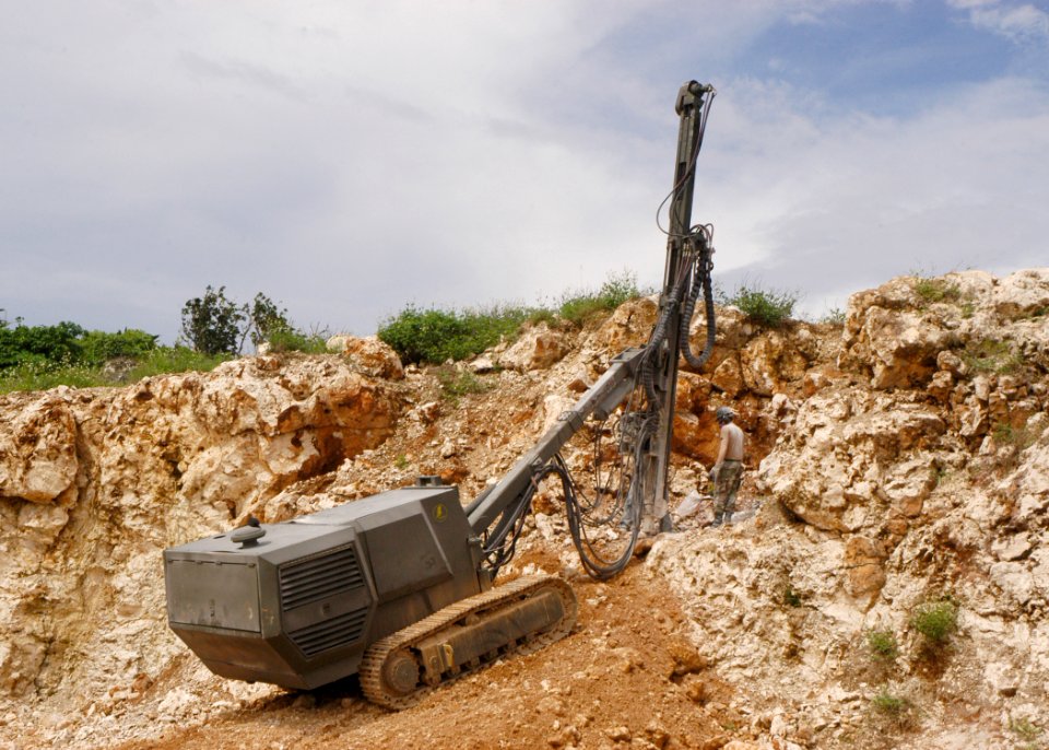 US Navy 070829-F-8678B-061 Construction Mechanic 2nd Class Andrew W. Duchscher guides Equipment Operator 2nd Class Daniel L. Romero, moving the boom of a hydraulic crawler mounted rock drill, while drilling holes at Orote Point