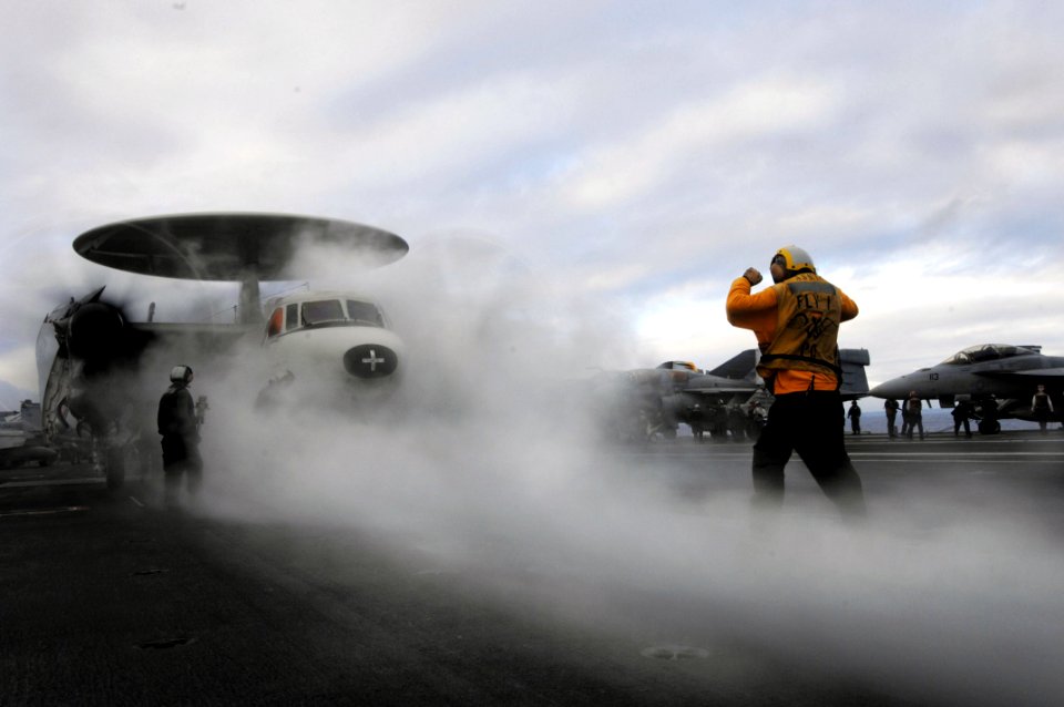 US Navy 070826-N-3729H-172 A flight deck aircraft director guides an E-2C Hawkeye, assigned to the Golden Hawks of Airborne Early Warning Squadron (VAW) 112, to the catapult for launch