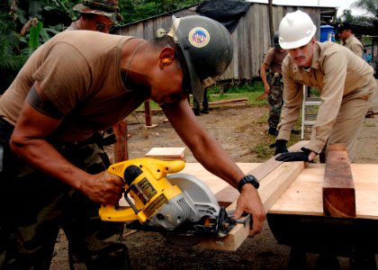 US Navy 070824-N-6278K-032 Equipment Operator 1st Class Manuel Gradillas, a Seabee with Construction Battalion Maintenance Unit (CBMU) 202 attached to Military Sealift Command hospital ship USNS Comfort (T-AH 20), saws a block photo