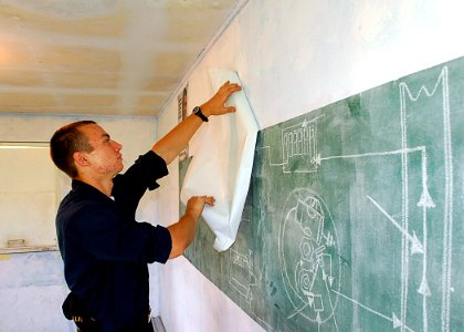 US Navy 070829-N-9421C-014 Airman Apprentice Andrei Nadtoka removes posters out of a classroom prior to painting during an engineering civic action program at Marshall High School in support of the Pacific Partnership mission