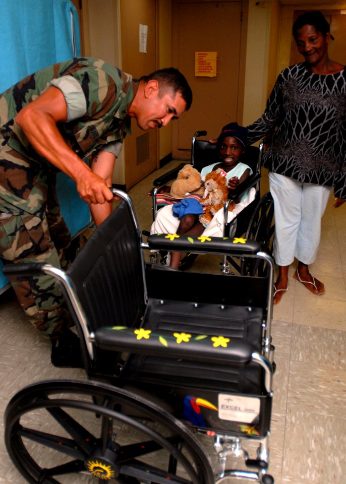US Navy 070827-N-4238B-008 Equipment Operator 1st Class Manuel Gradillas presents Ana Renteria with a wheelchair he painted for her aboard Military Sealift Command hospital ship USNS Comfort (T-AH 20) while her caregiver, Maria