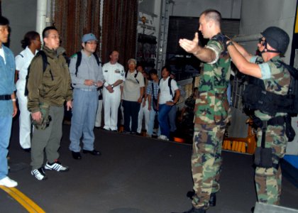 US Navy 070901-N-6710M-011 Ensign Michael H. Higgans demonstrates the proper personnel search techniques to Japanese drill evacuation drill participants on board dock landing ship USS Tortuga (LSD 46) photo