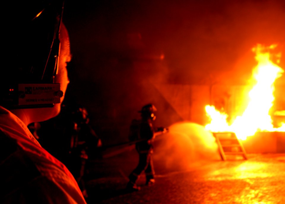 US Navy 070829-N-4965F-011 A safety observer watches as federal firefighters assigned to Navy Region Hawaii Federal Fire Department advance to combat a fire during an aircraft firefighting training evolution with the Mobile Air