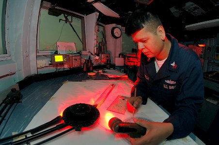 US Navy 070828-N-6501M-041 Quartermaster 1st Class Jose L. Ortega, of Whittier, Calif., reviews navigation charts on the bridge of mine warfare ship USS Gladiator (MCM 11) during a nighttime mine countermeasure exercise