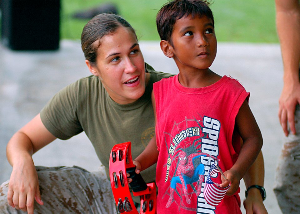 US Navy 070902-N-9421C-085 Cpl. Julia Roberts, of the U.S. Marine Forces Pacific Band, teaches a local youngster how to play the tambourine after a band performance at Uliga Park