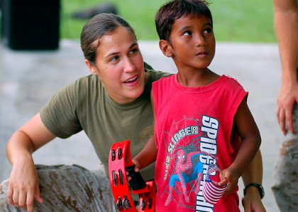 US Navy 070902-N-9421C-085 Cpl. Julia Roberts, of the U.S. Marine Forces Pacific Band, teaches a local youngster how to play the tambourine after a band performance at Uliga Park