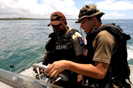 US Navy 070904-N-0989H-028 Master-at-Arms 3rd Class Sigredo Santiago, of U.S. Navy Expeditionary Training Command, trains a Dominican Republic sailor on the operation of a rigid hull inflatable boat photo