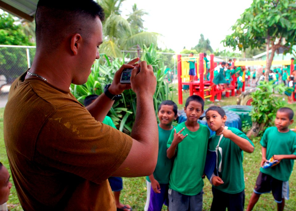 US Navy 070903-N-9421C-041 Steelworker 3rd Class Brian Laferriere, of Naval Mobile Construction Battalion (NMCB) 7, photographs Riarok Elementary School students as they enjoy their new playground, built by battalion personnel