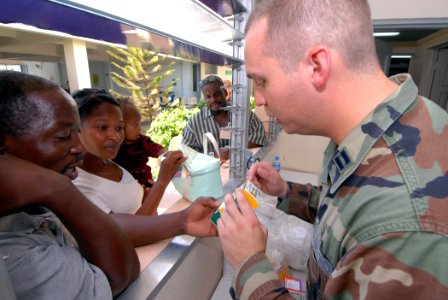 US Navy 070905-N-8704K-069 U.S. Air Force Capt. Brian Sydnor, attached to Military Sealift Command hospital ship USNS Comfort (T-AH 20), explains a child's prescription to her mother with help from Creole translator Ernst