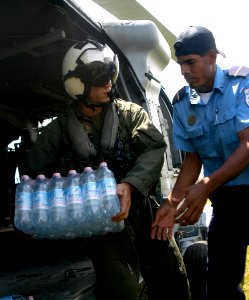 US Navy 070907-N-1189B-075 A U.S. Navy aircrewman attached to the multi-purpose amphibious assault ship USS WASP (LHD 1), carries bottles of water to the citizens of Puerto Cabezas