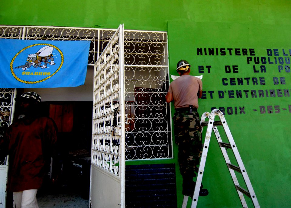 US Navy 070906-N-6278K-008 Builder 1st Class Manuel Gradillas, a Seabee assigned to Construction Battalion Maintenance Unit (CBMU) 202, paints a medical symbol on the wall of a local health training center