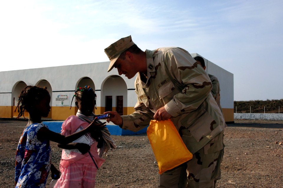 US Navy 070906-N-3931M-013 U.S. Navy Lt. Brian Baker, attached to the Combined Joint Task Force-Horn of Africa (CJTF-HOA), presents a gift to a local student during a school dedication ceremony