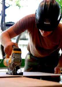 US Navy 070906-N-6278K-135 Equipment Operator 3rd Class Nathan Harper, a Seabee assigned to Construction Battalion Maintenance Unit (CBMU) 202, saws a board to reface cabinets for a laboratory at a local health training center photo