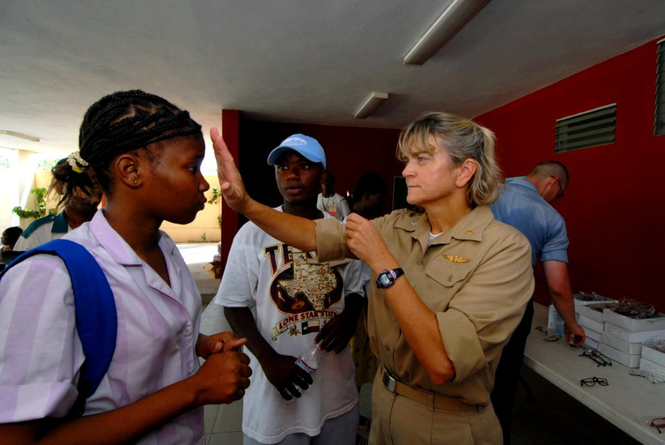 US Navy 070905-N-8704K-061 U.S. Navy Cmdr. Anna Stalcup, attached to Military Sealift Command hospital ship USNS Comfort (T-AH 20), performs optometry tests for a patient with the help of a Creole translator at Hôpital Universitaire