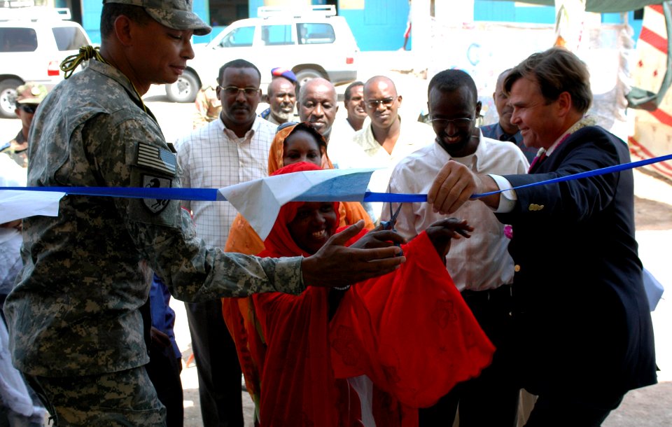 US Navy 070906-A-1286M-105 Brig. Gen. Sanford Holman, Combined Joint Task Force-Horn of Africa deputy commander and U.S. Ambassador to Djibouti, Stuart Symington assist in cutting a ribbon with a local teacher