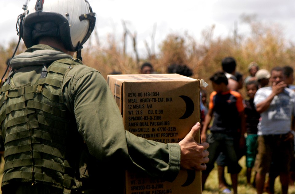 US Navy 070907-N-1189B-033 A U.S. Navy aircrewman attached to the multi-purpose amphibious assault ship USS WASP (LHD 1) carries a box of Meals Ready to Eat (MRE) to the citizens of Puerto Cabezas, Nicaragua