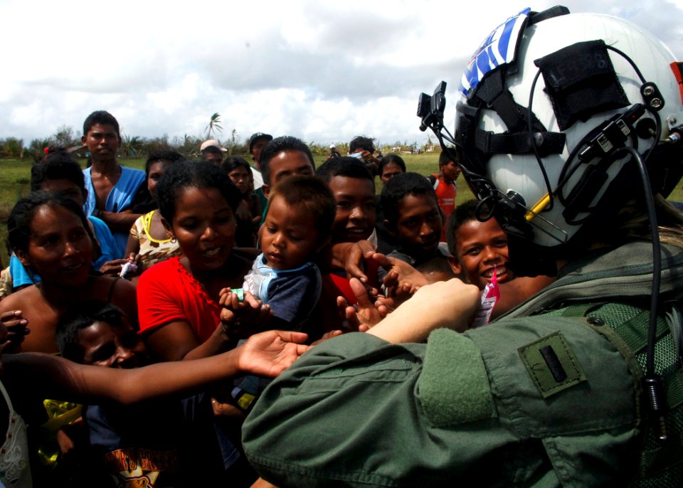 US Navy 070907-N-7540C-033 A U.S. Navy pilot hands out candy to local children while delivering food and water from the multipurpose amphibious assault ship USS Wasp (LHD 1)