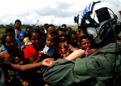 US Navy 070907-N-7540C-033 A U.S. Navy pilot hands out candy to local children while delivering food and water from the multipurpose amphibious assault ship USS Wasp (LHD 1)