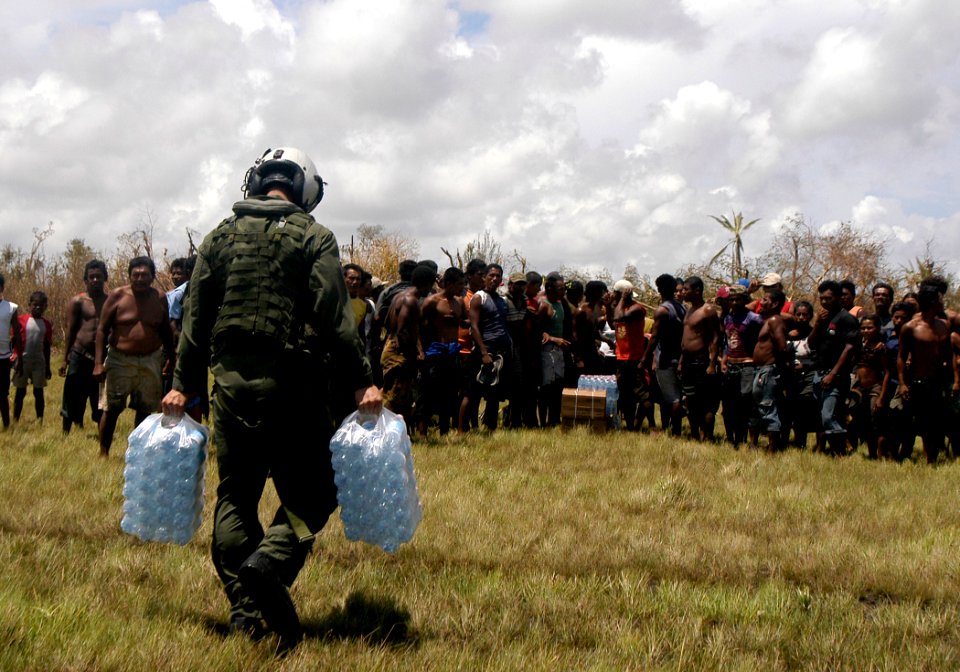 US Navy 070907-N-1189B-027 A U.S. Navy aircrewman attached to the multi-purpose amphibious assault ship USS WASP (LHD 1) carry bottles of water to the citizens of Puerto Cabezas