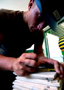 US Navy 070906-N-6278K-015 Builder 2nd Class Charles Page, a Seabee assigned to Construction Battalion Maintenance Unit (CBMU) 202, measures a board to reface cabinets for a laboratory at a local health training center photo