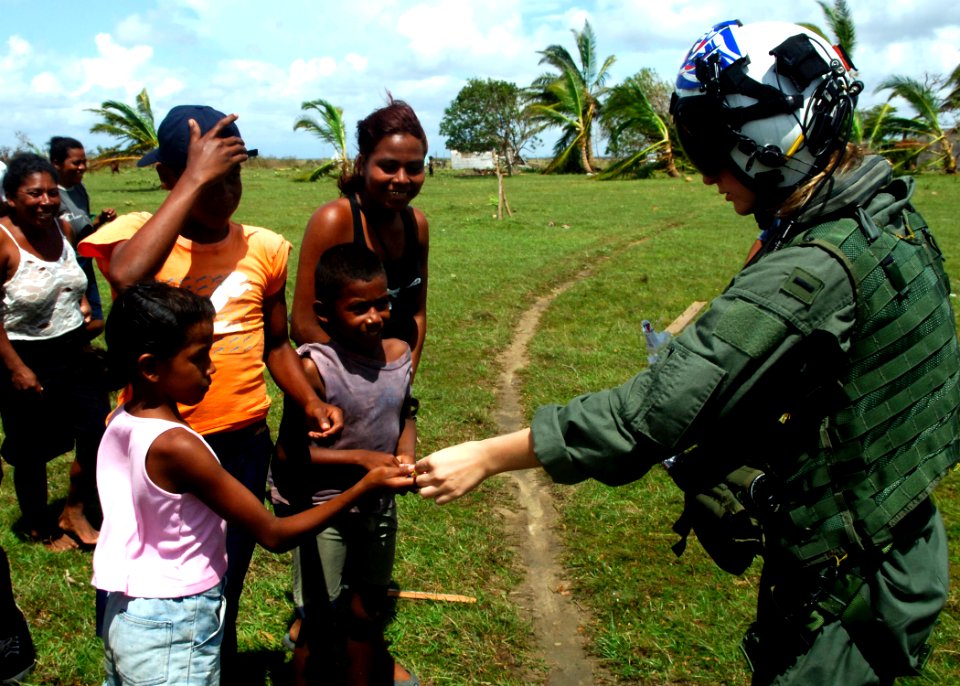 US Navy 070907-N-7540C-018 A U.S. Navy pilot hands out candy to local children while delivering food and water from the multipurpose amphibious assault ship USS Wasp (LHD 1)
