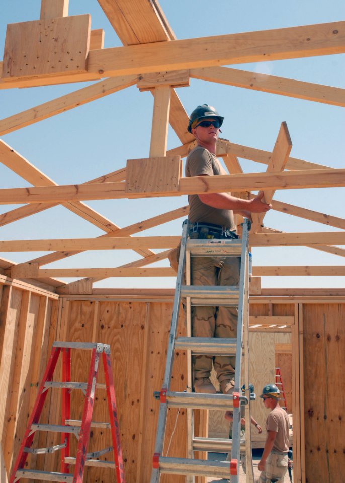 US Navy 070909-N-3560G-074 Builder 3rd Class Mason Lynn, assigned to Naval Mobile Construction Battalion (NMCB) 4, constructs the roof on a berthing facility