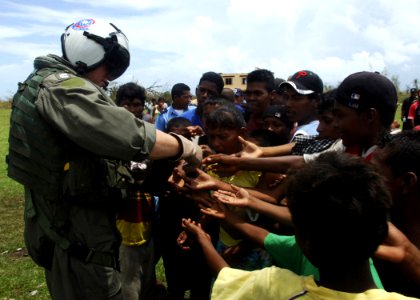 US Navy 070907-N-7540C-056 A U.S. Navy pilot hands out candy to local children while delivering food and water from the multipurpose amphibious assault ship USS Wasp (LHD 1) photo