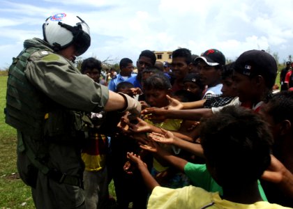 US Navy 070907-N-7540C-056 A U.S. Navy pilot hands out candy to local children while delivering food and water from the multipurpose amphibious assault ship USS Wasp (LHD 1)